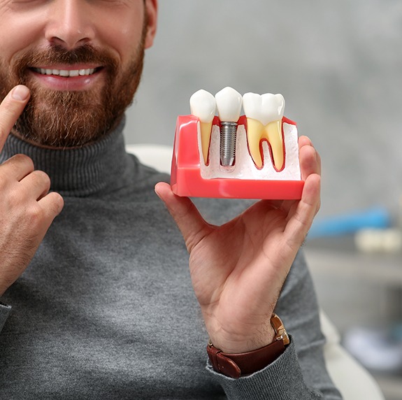 Patient holding a model of a dental implant