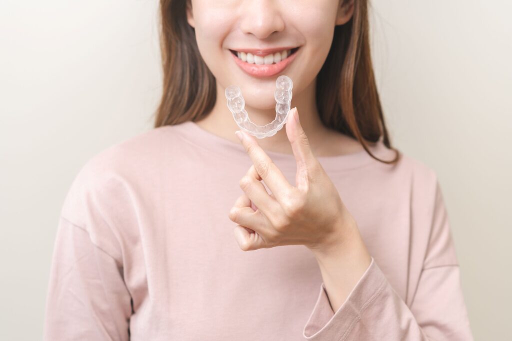 Nose-to-chest view of woman smiling holding Invisalign