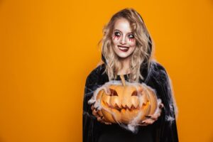 Woman in a Halloween costume holding a jack-o’-lantern
